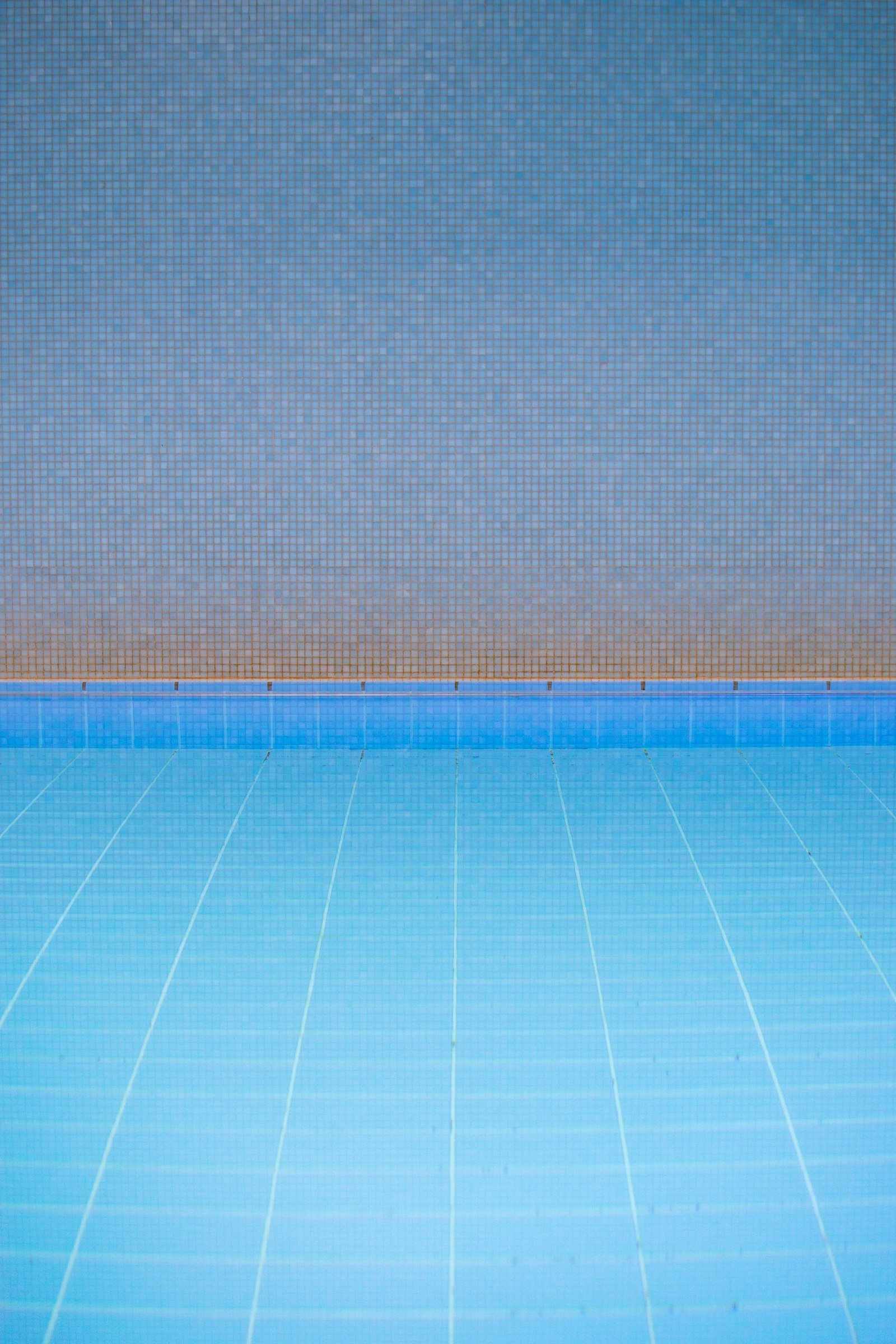Empty swimming pool with worn blue tile floor before renovation